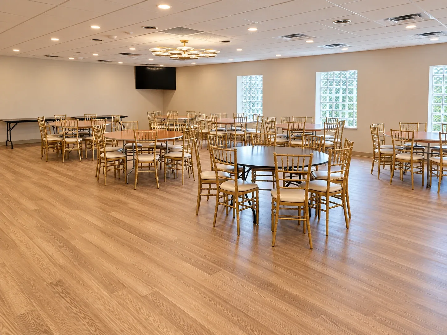 The hall set with round tables and gold chairs, looking toward the screen.